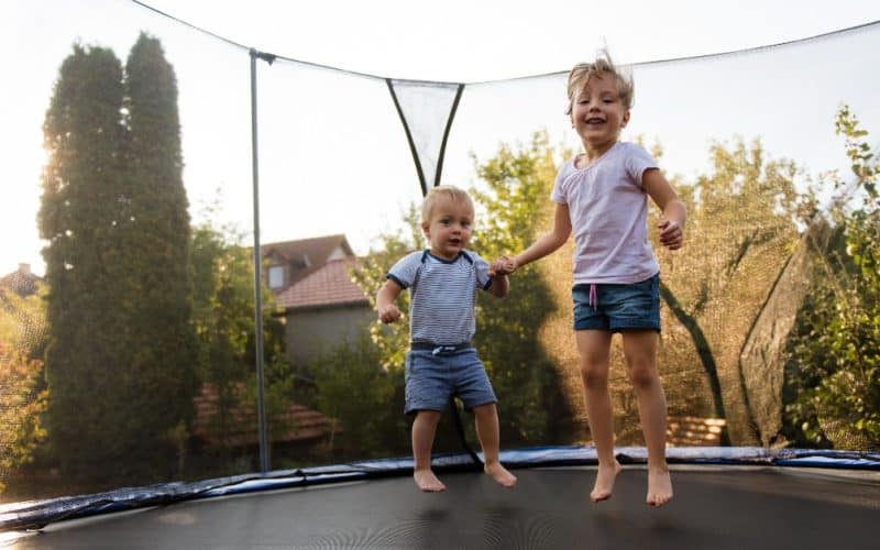 siblings jumping on a trampoline
