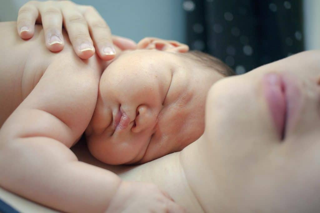 baby sleeping on top of his mother