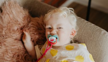 baby with a pacifier lying on a sofa