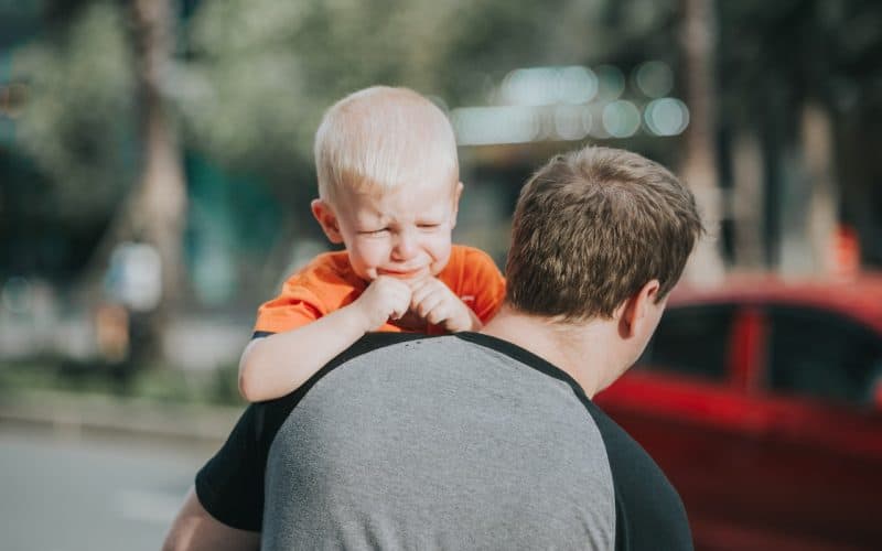 dad carrying crying baby boy