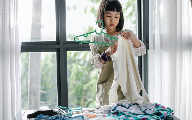 girl putting clothes on hanger