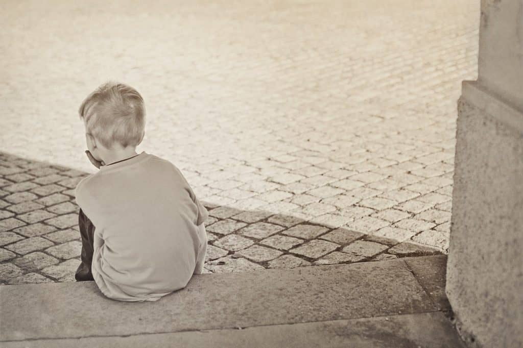 little boy sitting on concrete