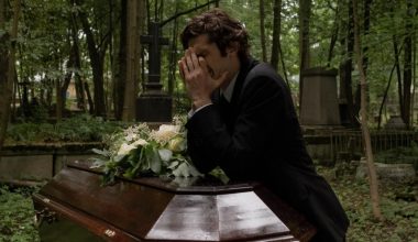 man crying beside a coffin