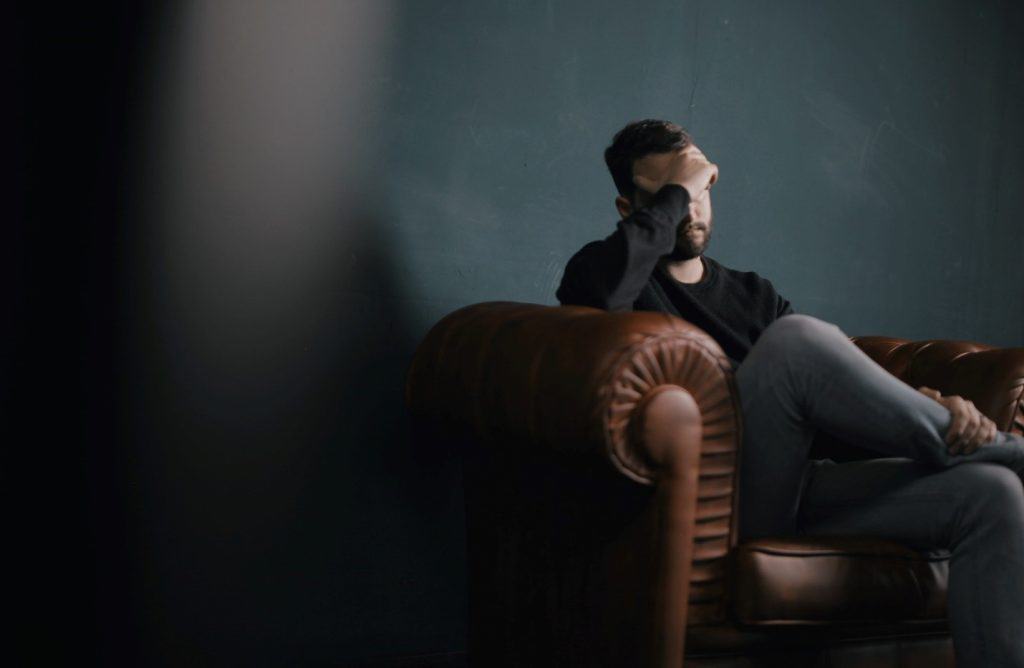 man sitting on a sofa holding his head