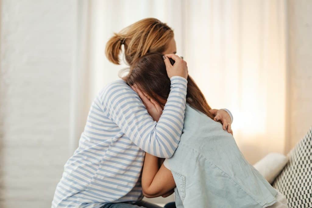 mom comforting crying daughter