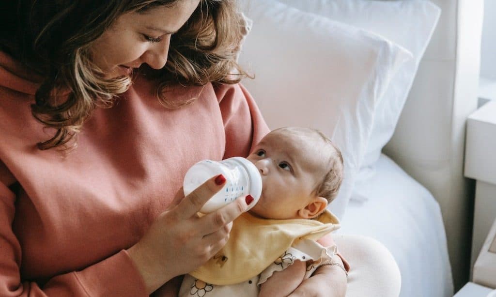 mom feeding baby with bottled milk