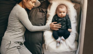 mom sleeping with baby on a bassinet