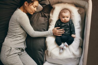 mom sleeping with baby on a bassinet