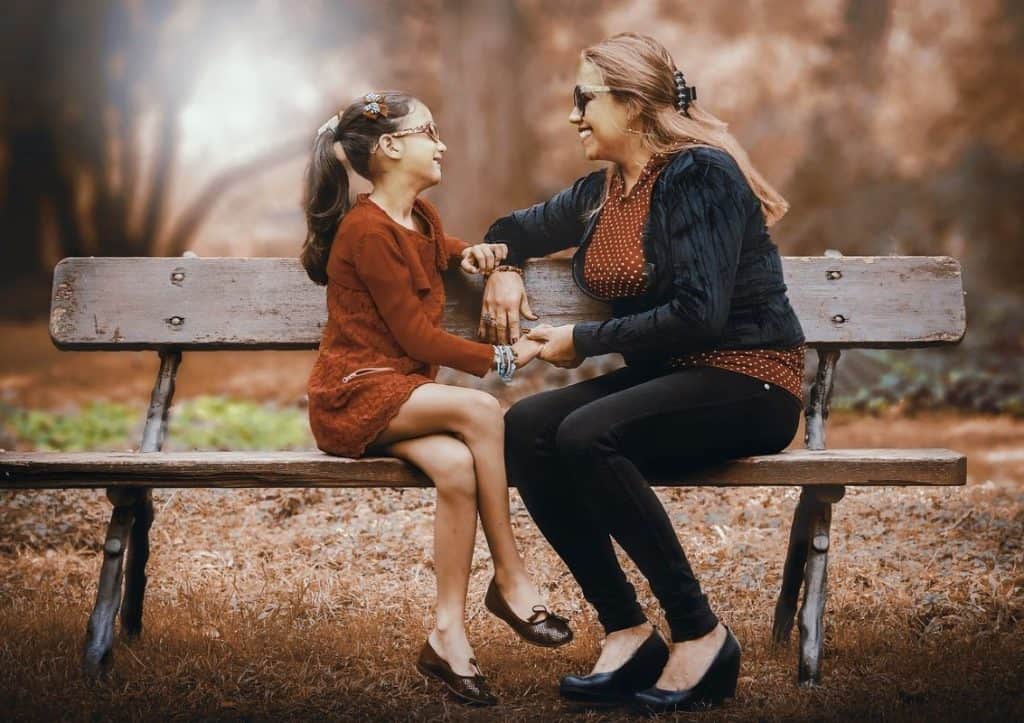 mother and daughter sitting on a bench