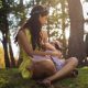 mother breastfeeding while sitting on grass