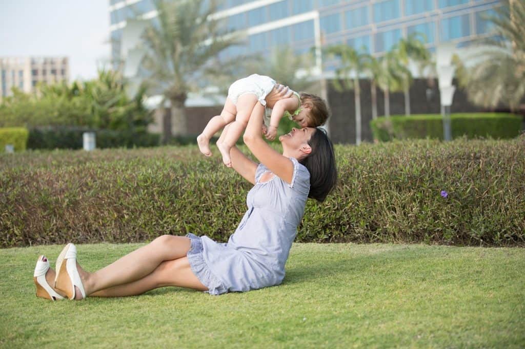 woman holding baby up the air
