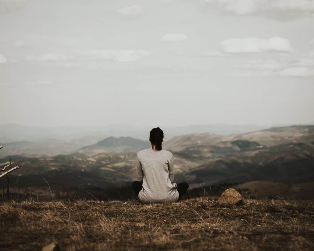 woman sitting alone on top of a mountain