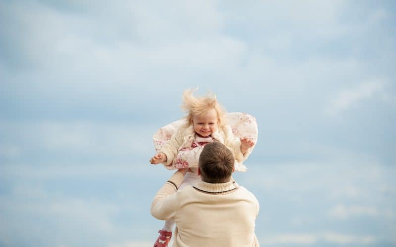father carrying baby girl up in the air
