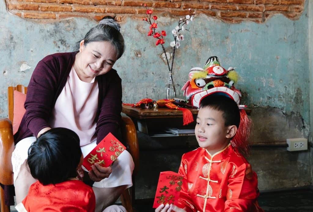 grandmother giving red envelops to grandchildren