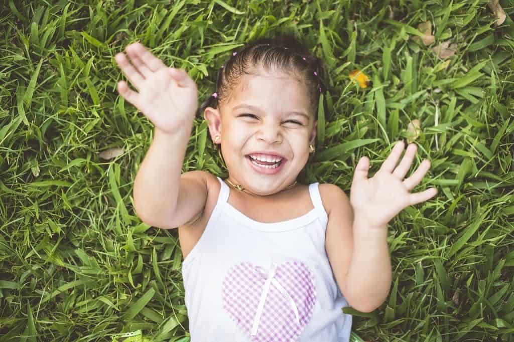 little girl laughing on grass