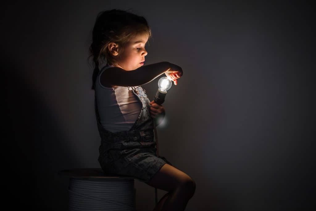 little girl playing with a light bulb
