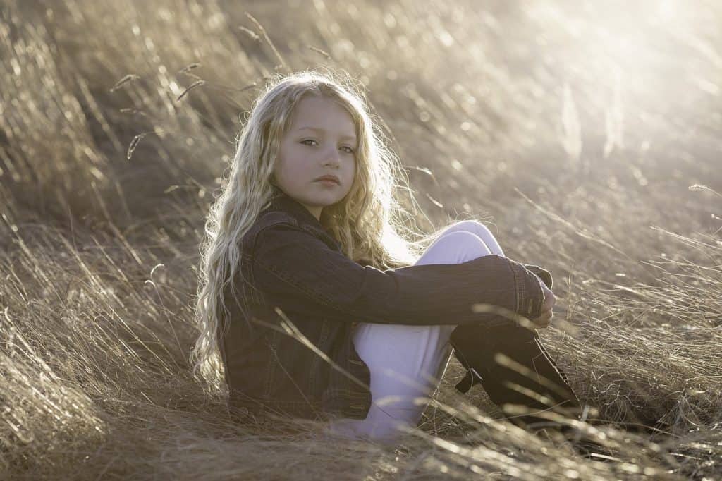 little girl sitting on a field