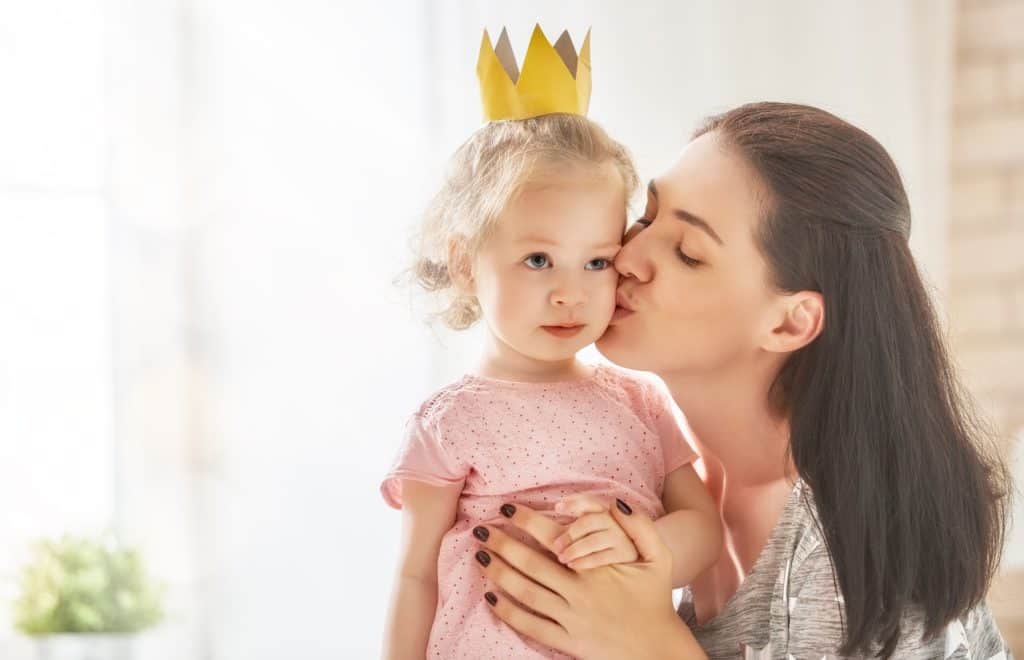 mom kissing baby girl wearing a crown