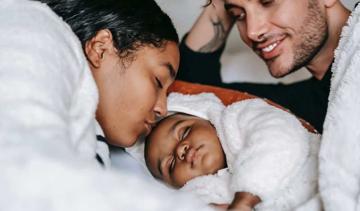 mom kissing sleeping baby's forehead