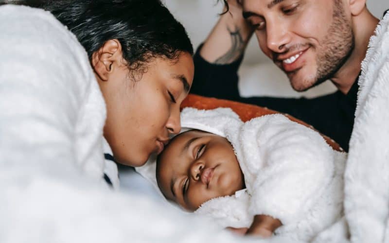 mom kissing sleeping baby's forehead