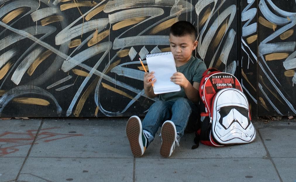 young boy sitting while holding notebook