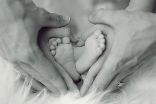 couple forming heart shape on their baby's feet