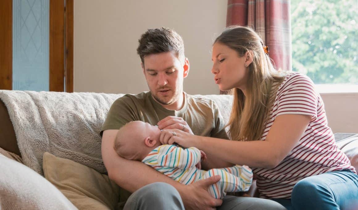 couple sitting on a sofa with baby