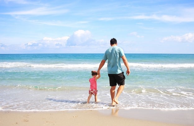 dad and daughter walking on a beach