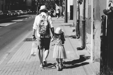 father and daughter walking on the sidewalk