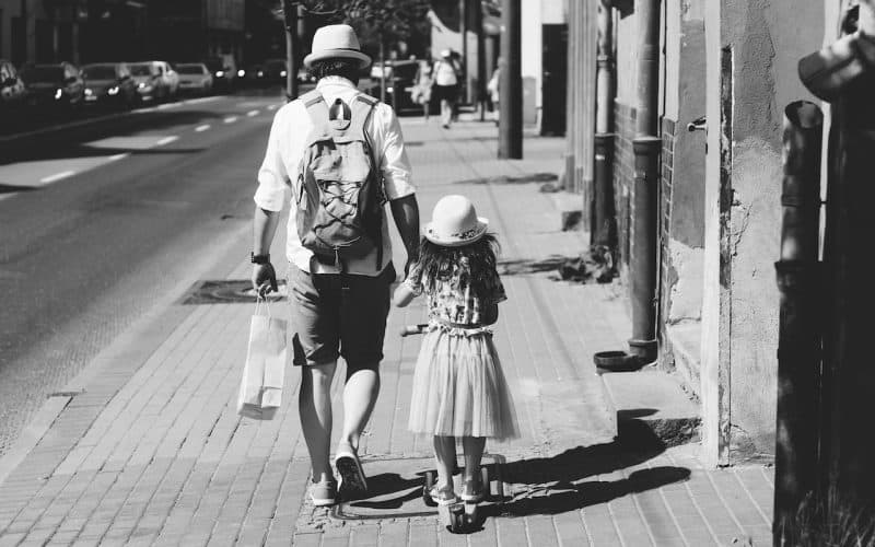 father and daughter walking on the sidewalk