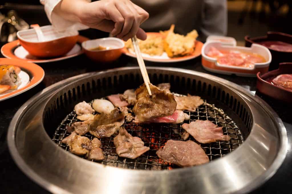 hand picking beef on a grill