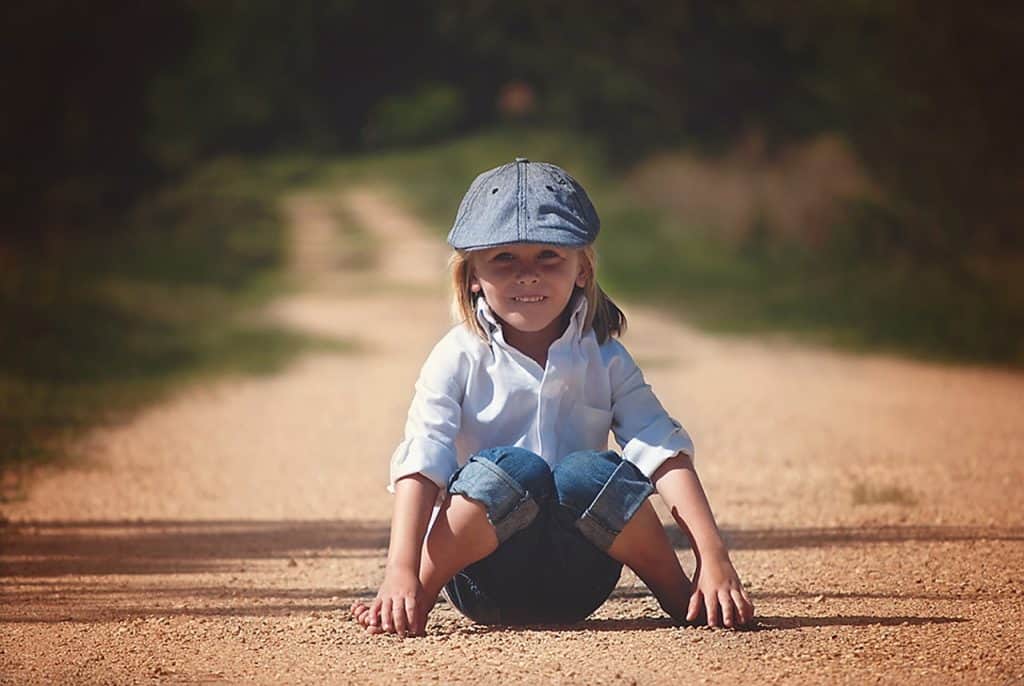 little boy sitting on a road