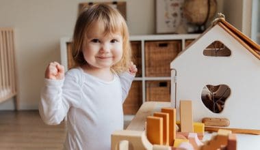 little girl playing with doll house