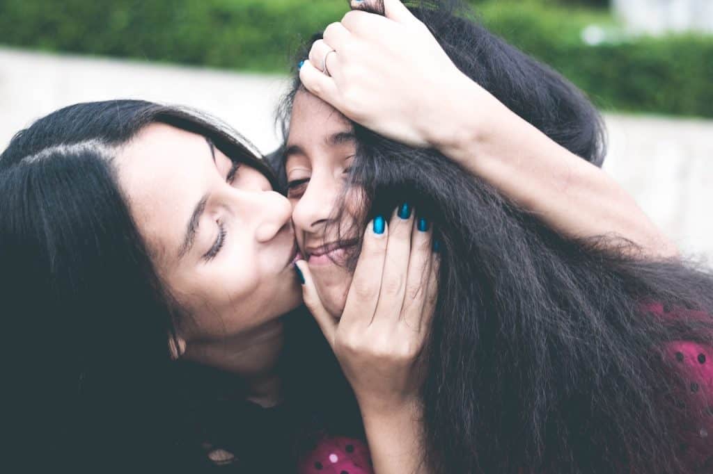 mom kissing daughter