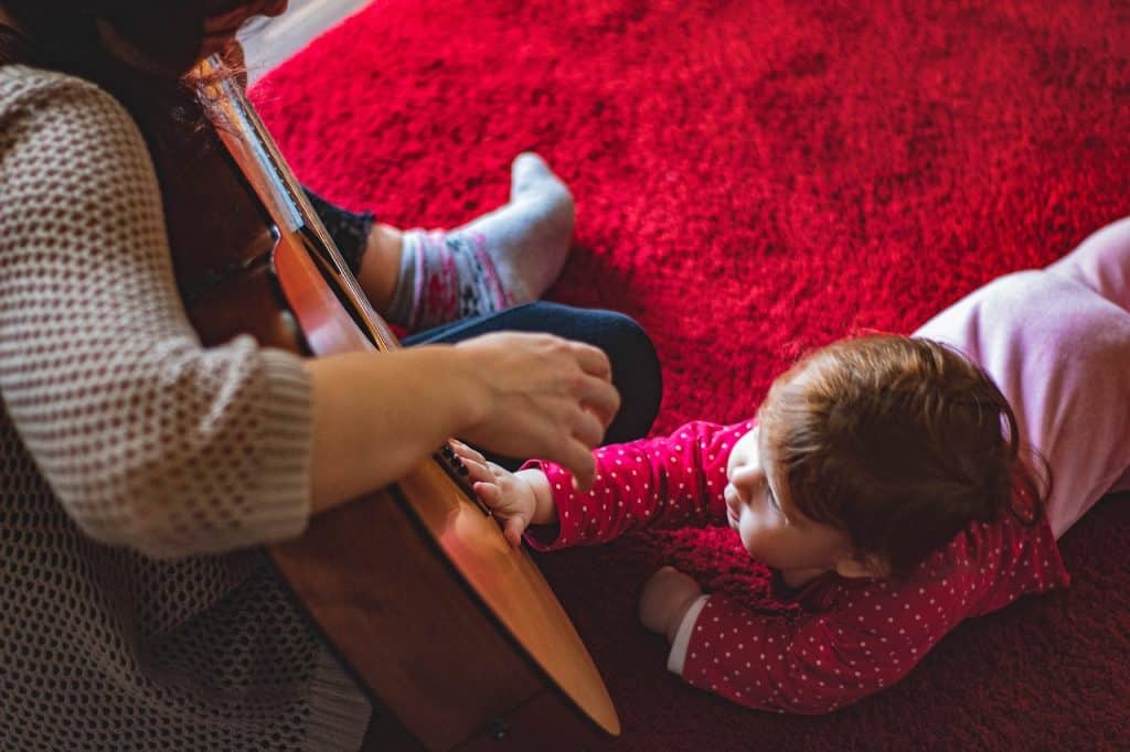 mom playing guitar around baby