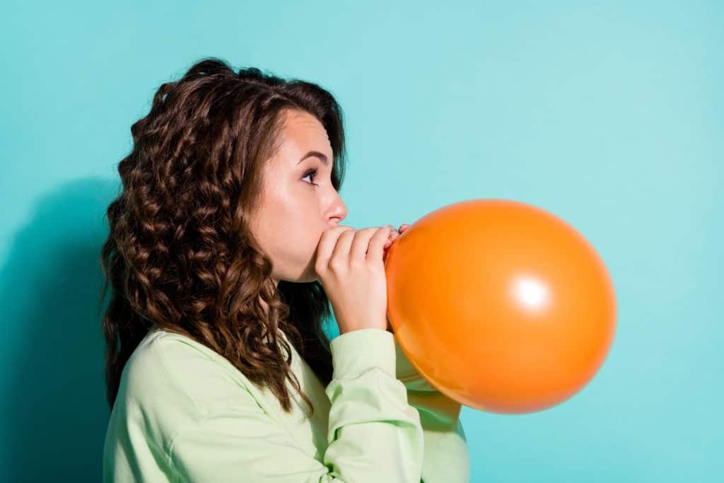 woman blowing up a balloon