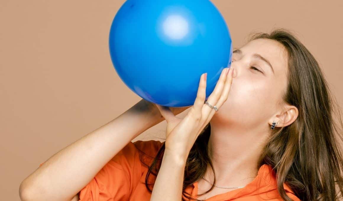woman blowing up a blue balloon