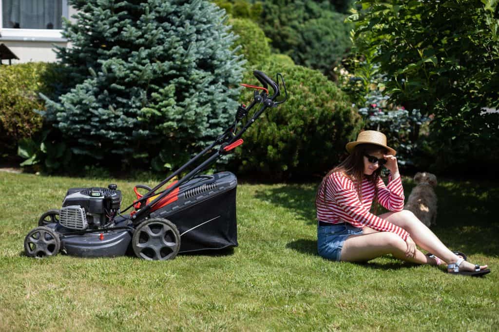 woman sitting beside a mower
