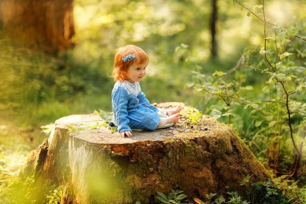 baby girl sitting on cut out tree
