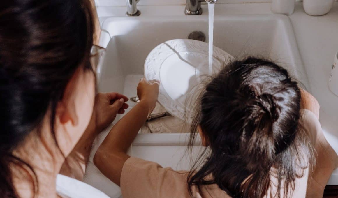 kid washing dishes with mom