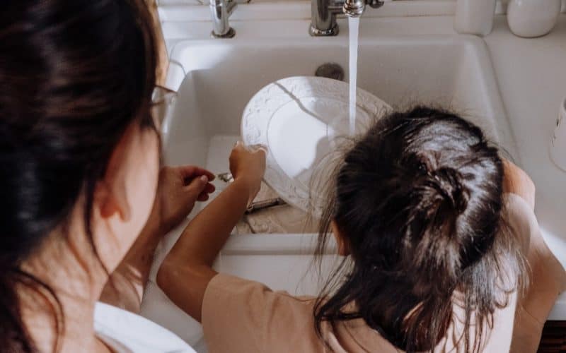 kid washing dishes with mom