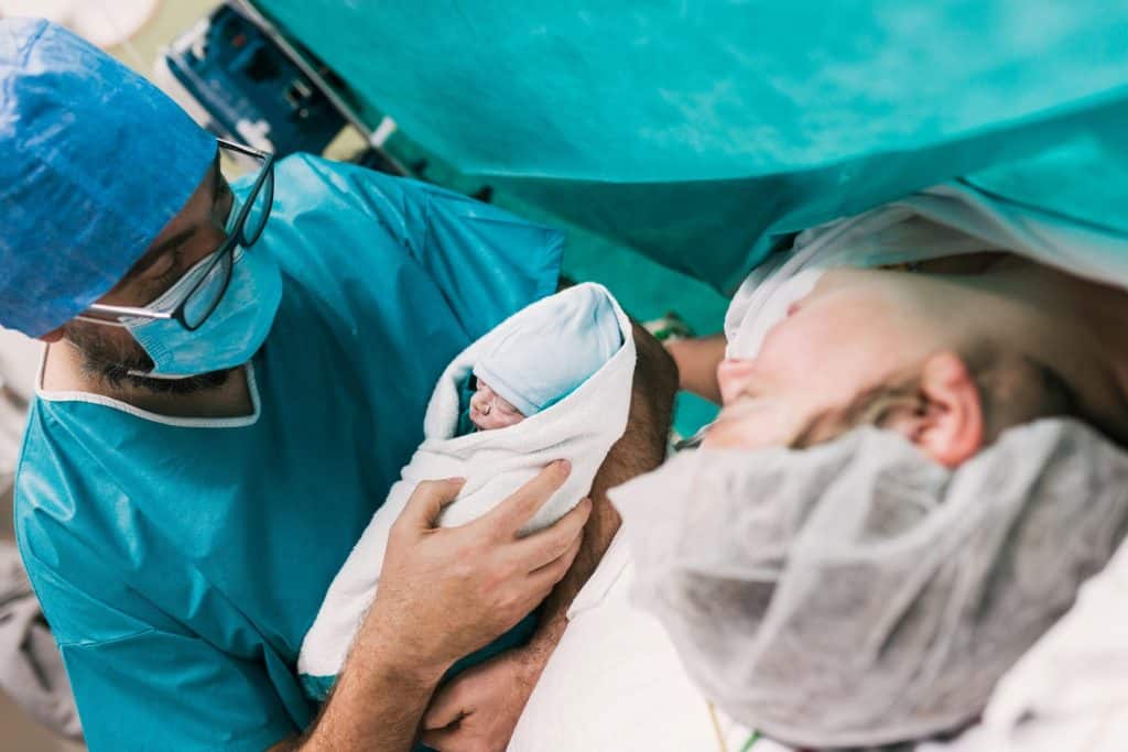 doctor showing newborn baby to mom