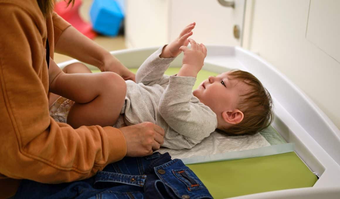 mom putting baby on a changing table