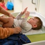mom putting baby on a changing table
