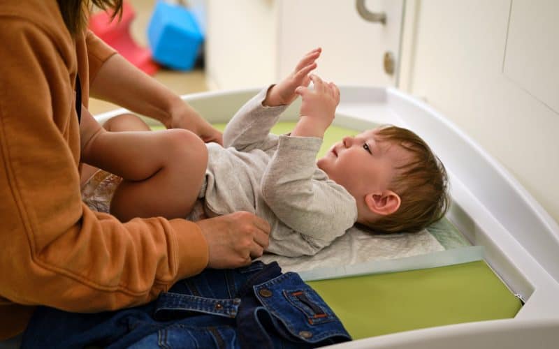 mom putting baby on a changing table