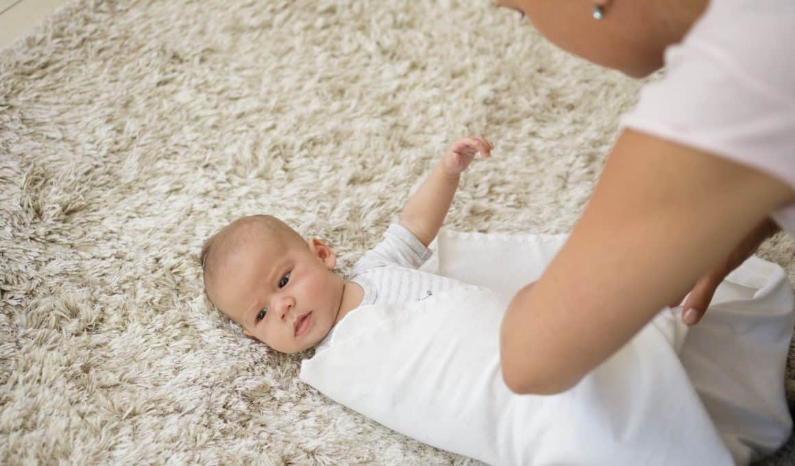 mom wrapping baby on a blanket