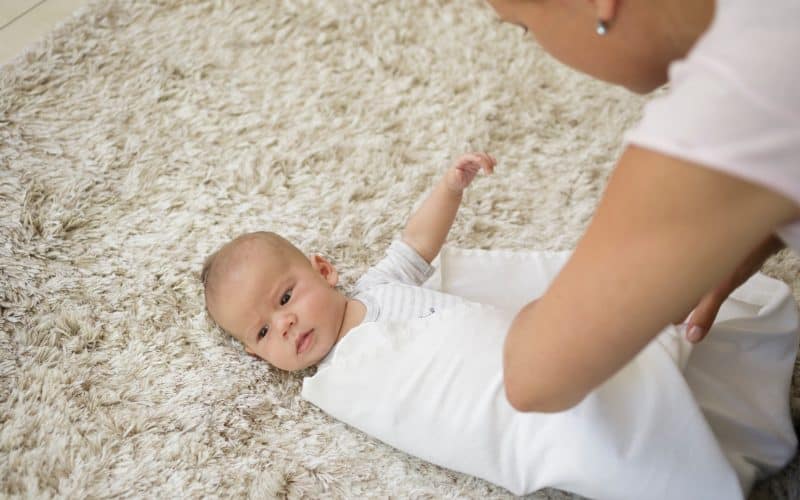 mom wrapping baby on a blanket