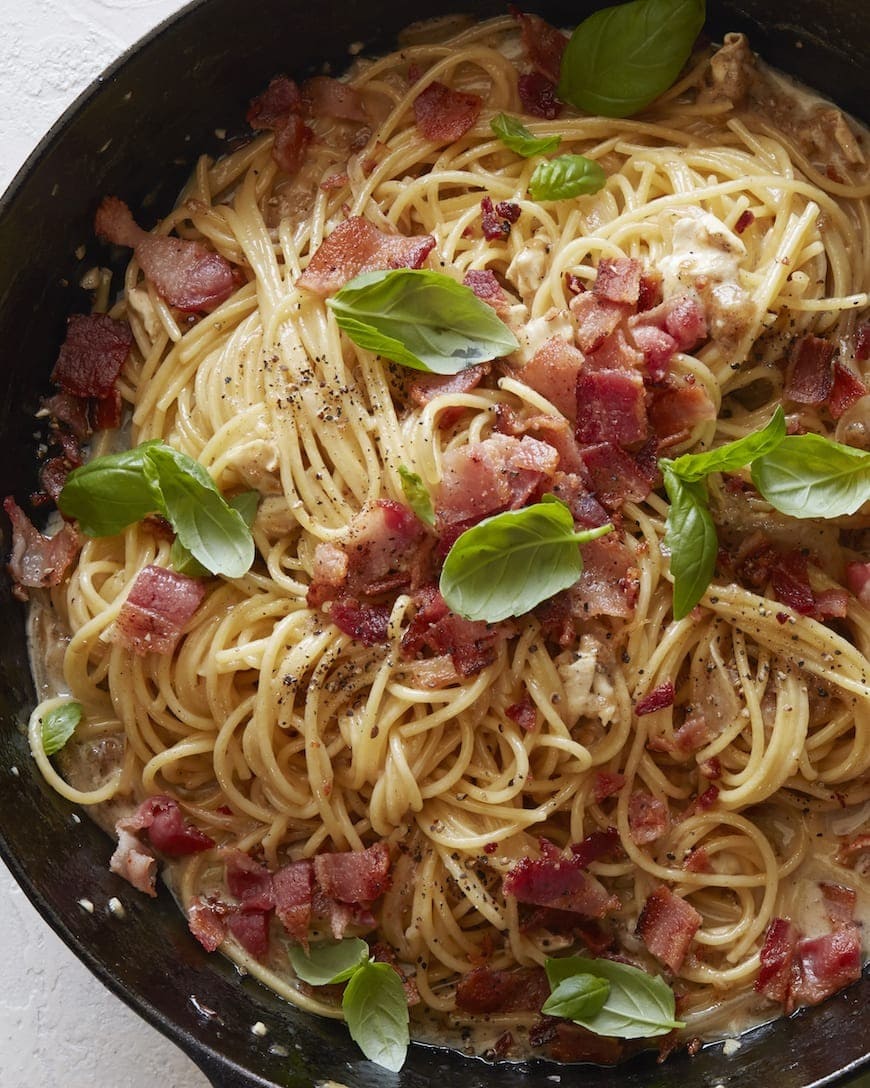 Pasta with brie, bacon and basil on a skillet