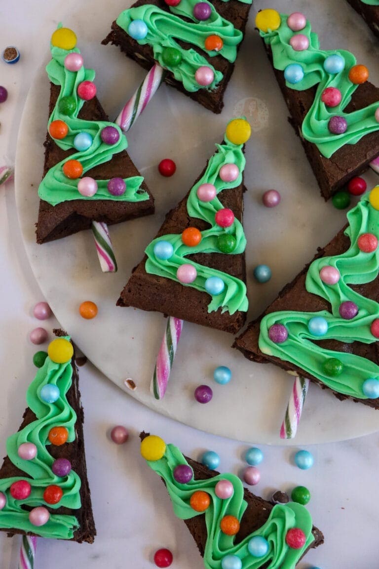 Christmas tree shaped brownies decorated with green frosting and candies.