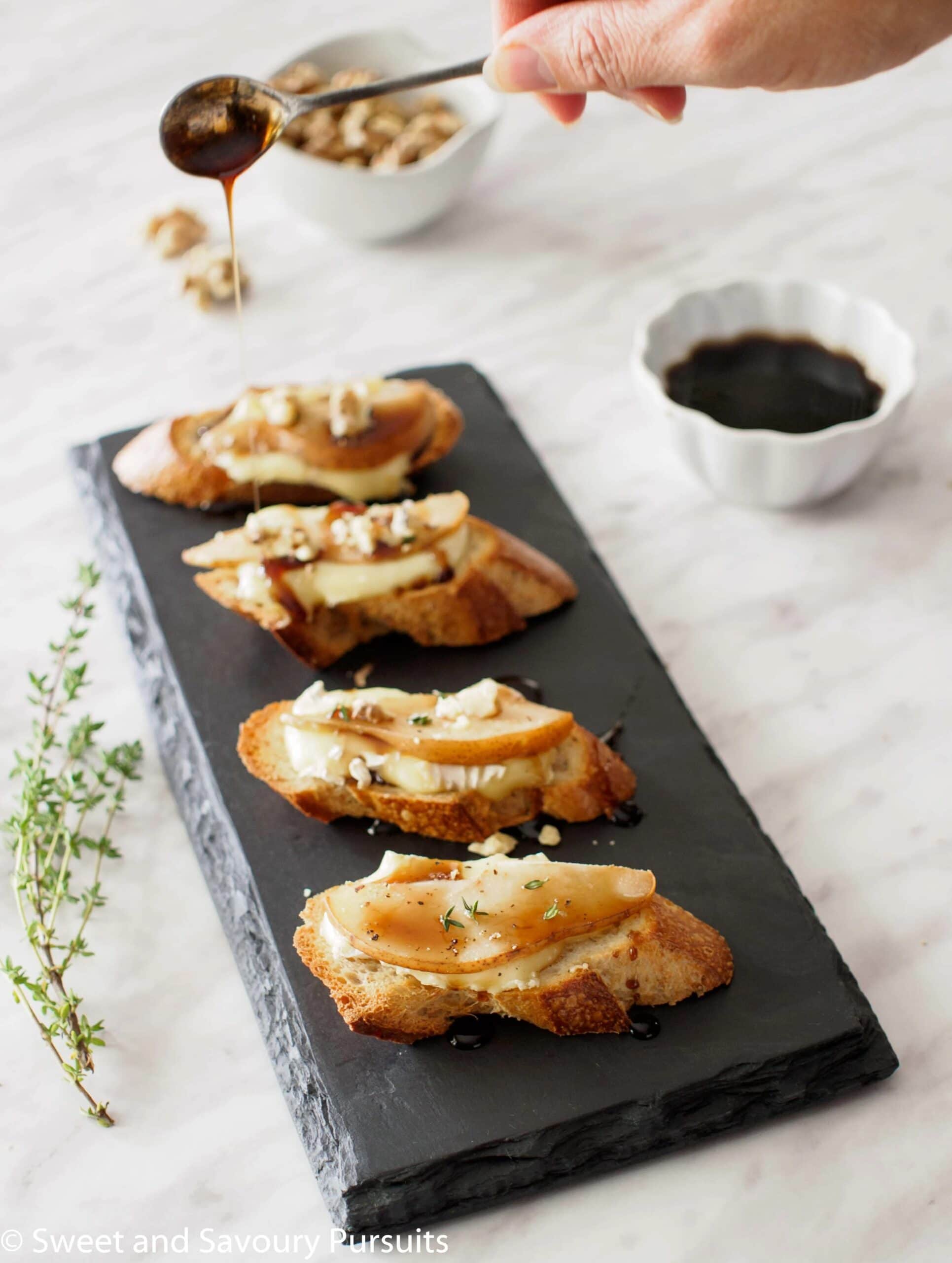 Crostini topped with brie spread and a slice of pear.